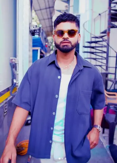 Shreyas Iyer standing confidently on a cricket field, wearing his Delhi Capitals jersey.