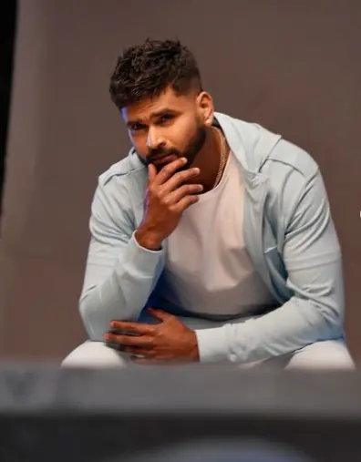 Shreyas Iyer standing confidently on a cricket field, wearing his Delhi Capitals jersey.