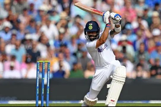 "Virat Kohli, Indian cricketer, celebrating a century on the cricket field with his bat raised and a triumphant smile."

