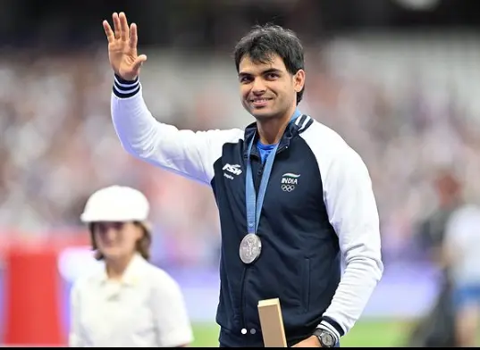 "Neeraj Chopra celebrating after winning a gold medal in javelin, holding the Indian flag with a joyful smile."

