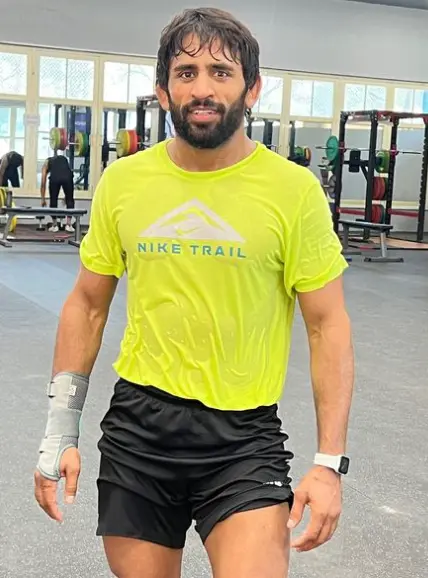 "Bajrang Punia, Indian wrestler, proudly holding his gold medal on the podium, representing his numerous international achievements in wrestling."

