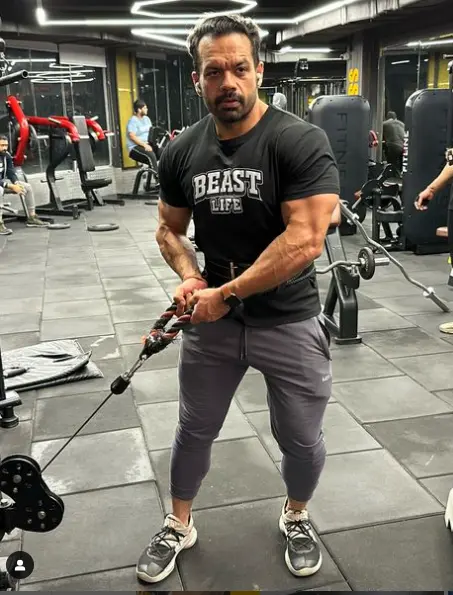 A full-body image of Gaurav Taneja, highlighting his strong build and height, adding to his presence as a fitness influencer and public figure.