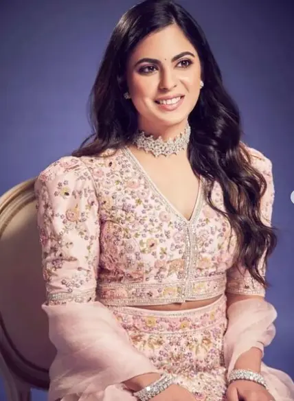 "Isha Ambani, Indian businesswoman, wearing a traditional outfit, speaking at a corporate event, with a confident smile."